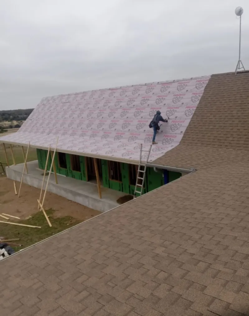 Worker preparing underlayment for a metal roof installation in Montrose